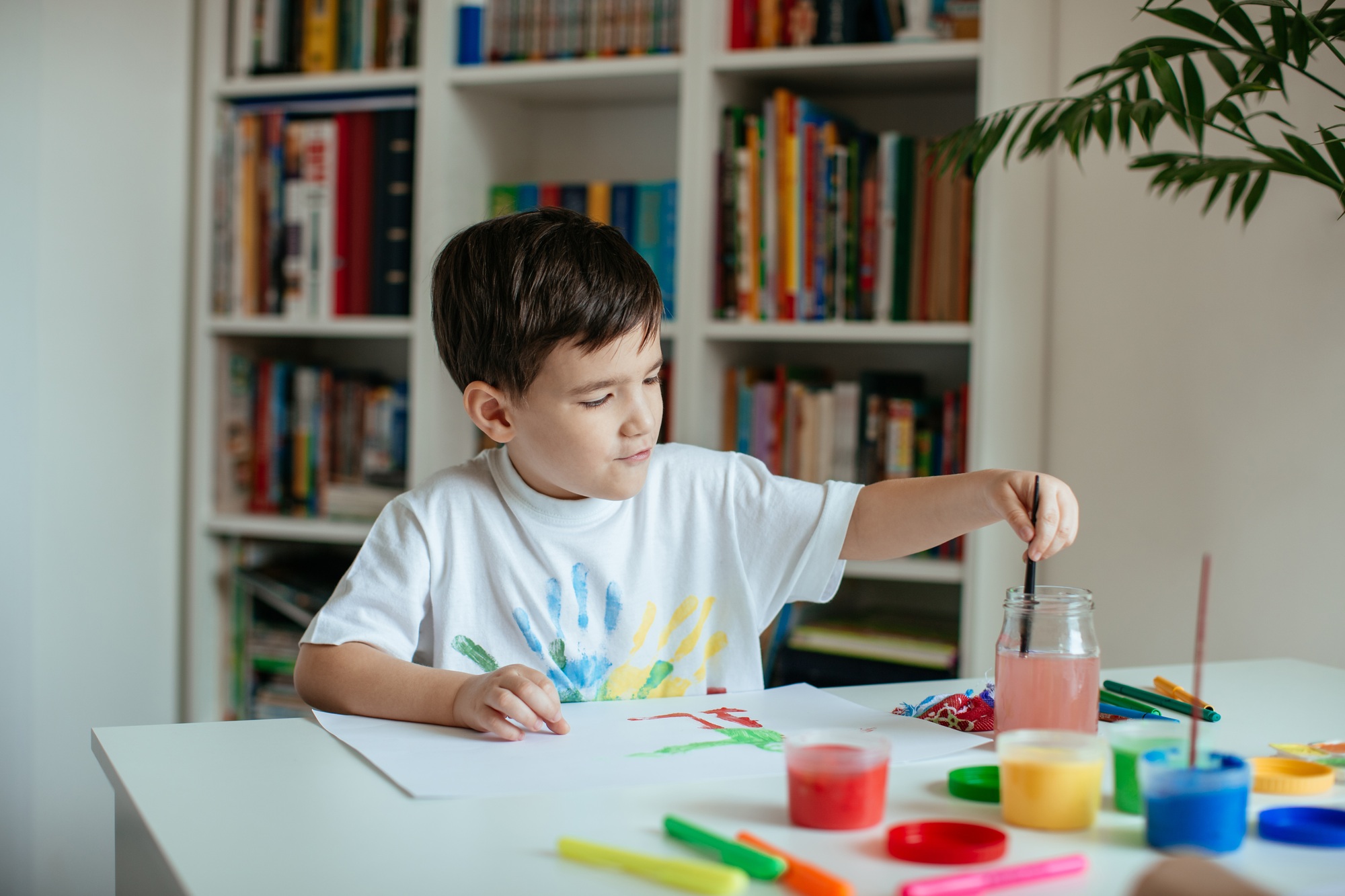 Cute 5 year old boy enjoying painting with watercolor.