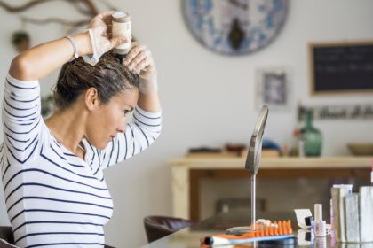 Young beautiful woman colouring her hair at home herself with chemical products